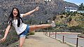 Eine junge Frau balanciert auf einem Stein - im Hintergrund der Hollywood-Schriftzug in den Bergen bei LA